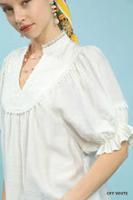 Off-white umgee blouse features smocked yoke with delicate lace trim and elegant ruffle sleeves for a feminine look