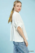 Off-white Umgee blouse features smocked yoke and delicate lace trim with ruffle sleeves at the neckline