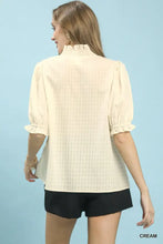 Cream-colored umgee blouse with textured check ruffle pattern, puffed sleeves, ruffled cuffs, and high neckline