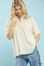 Cream-colored umgee textured henley blouse with ruffle cuffs and subtle embroidered collar detail in textured fabric