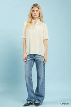 Cream-colored umgee textured henley blouse featuring a subtle pattern and ruffle cuffs on short sleeves