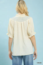 Cream-colored umgee textured henley blouse with delicate lace neckline and ruffle cuffs on sleeves