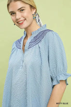 Misty blue umgee textured henley blouse with navy embroidery at neckline and ruffle cuffs on cotton fabric