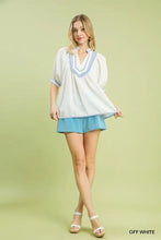 Off-white short-sleeved top with light blue jacquard contrast trim around v-neck and sleeve cuffs by umgee textured jacquard