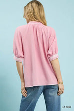 A soft pink umgee textured jacquard blouse with rolled three-quarter sleeves and jacquard contrast trim collar