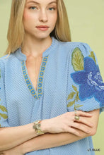 Light blue umgee textured jacquard blouse with embroidered floral design and gold-trimmed jacquard v neck neckline