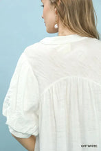 Off-white umgee blouse with textured lace trim v-neck, slightly crinkled fabric, and puffy short sleeves