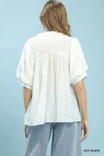 Off-white umgee blouse with puffed short sleeves and gathered back featuring textured lace trim v-neck boho design