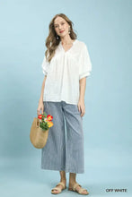 Off white textured short-sleeved umgee blouse with v-neckline and subtle ruching featuring textured lace trim detail