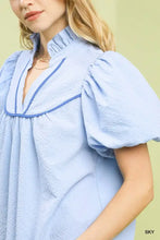 Umgee light blue textured puff sleeve blouse with ruffled high collar and navy piping along the neckline