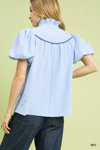 Umgee light blue textured puff sleeve blouse features ruffled high neckline with navy trim for elegant style