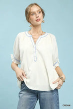 Cream-colored lightweight umgee textured split neck puff sleeve top with delicate blue embroidery on neckline and cuffs