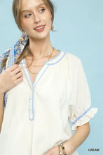 Cream-colored Umgee textured split neck puff sleeve top with delicate blue embroidered trim on neckline and cuffs