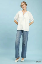 White umgee textured split neck puff sleeve top with blue embroidery paired with classic denim jeans