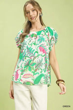 A woman wears an Umgee tropical paisley puff sleeve blouse in vibrant green and pink floral print with short puffed sleeves