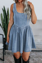 A light blue denim skater dress with a square neckline fitted bodice flared skirt and bow tie detail
