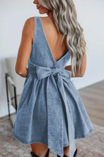Light blue denim skater dress with deep v-back and bow tie waist detail shown from the back side