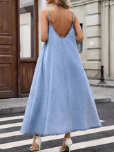 A light blue denim cami dress featuring thin straps and a deep back cutout shown from the back side