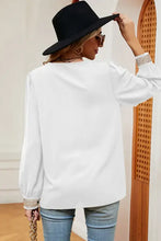 Woman in long sleeve V-neck T-shirt, blue jeans, and black hat