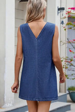 Blue denim sleeveless dress with v-back and straight hemline shown from the back in a sleeveless denim dress style