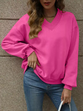 A vibrant pink v neck solid color casual sweatshirt with long sleeves and slightly stretchy material in relaxed fit