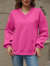 A vibrant pink v-neck solid color casual sweatshirt with long sleeves ribbed cuffs and slightly stretchy material