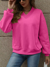 A vibrant pink v-neck solid color casual sweatshirt with long sleeves ribbed cuffs and slightly stretchy material