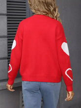 Red knit cardigan with white heart pattern patches at shoulder seam