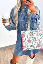 A white tote bag with a vibrant pink green and purple floral pattern paired with a vintage wash denim dress