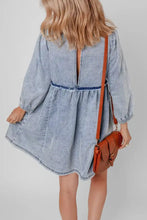 Light blue vintage wash denim dress with back slit elasticated cuffs and pockets shown from the back side