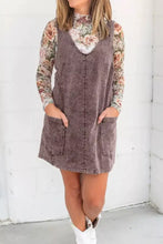 A dusty purple vintage wash denim overall dress with high neckline and two front pockets in wash denim material