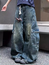 Vintage wash wide leg cargo jeans in dark-wash denim with large side pockets and faded distressed detailing