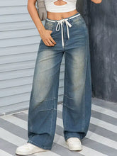High-waisted vintage wash wide leg denim jeans in faded blue with white drawstring waistband for casual wear