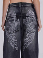 Back side of dark wash vintage wash wide leg jeans with prominent white angel wing designs on back pockets