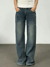 Vintage wash wide leg jeans in faded blue denim with subtle distressing and raw hem detailing