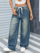 Vintage wash wide leg jeans in faded blue denim with white drawstring waistband for casual comfort