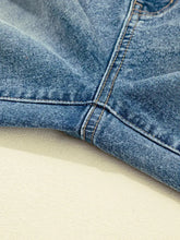 A close-up of medium-wash denim fabric showing vintage washed seam detail and stitching on shift jeans