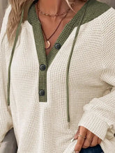 Cream-colored waffle knit button detail drawstring hoodie with olive green contrast panel in slightly stretchy material