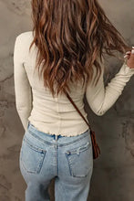 Woman in waffle knit half snap long sleeve top with lettuce trim, jeans, bag