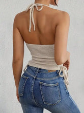 Beige waffle knit halter neck cami with crocheted texture tied back straps and a cinched waist