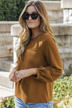 Woman in waffle knit round neck long sleeve top, rust textured, jeans, cat-eye sunglasses