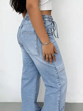 Light-wash denim wash wide leg cargo jeans featuring a high-rise drawstring waistband and wide leg cargo cut