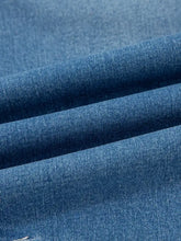 Blue denim fabric with a textured woven pattern on washed cuffed barrel jeans for casual wear