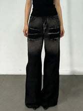 Black distressed washed wide leg jeans with ripped patches on the thighs in a wide leg jeans style