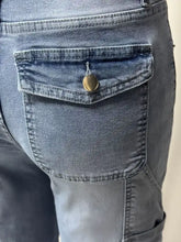 A close-up of the back side of dark blue denim washed wide leg jeans with a metallic button closure on the pocket