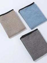 Three folded napkins in beige, blue, gray with black edges on car seat cover