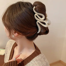 Wavy beige acrylic hair claw clip securing long brown hair bun