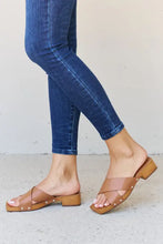 Person in blue skinny jeans wearing brown wooden clog mule sandals