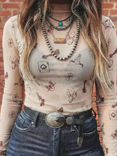 A silver-toned ornate belt buckle with intricate engravings paired with a slim fit mesh western print mock neck top