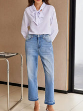 Light blue denim whiskered wash cropped jeans with a straight-leg cut and raw hem frayed cuffs